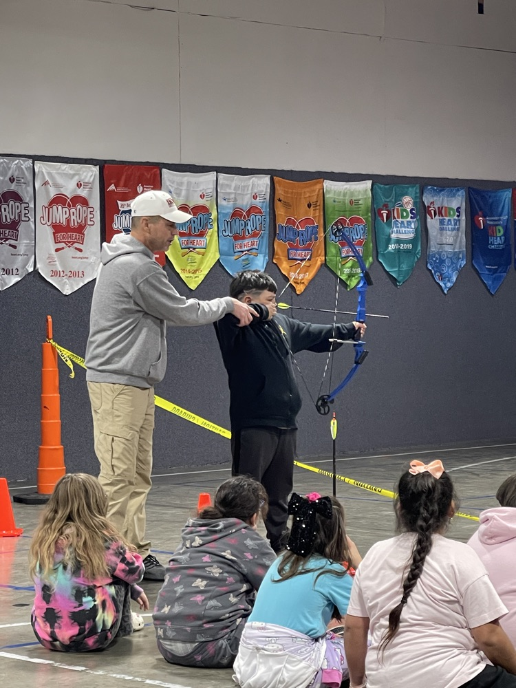 Teacher showing a student how to fire a bow