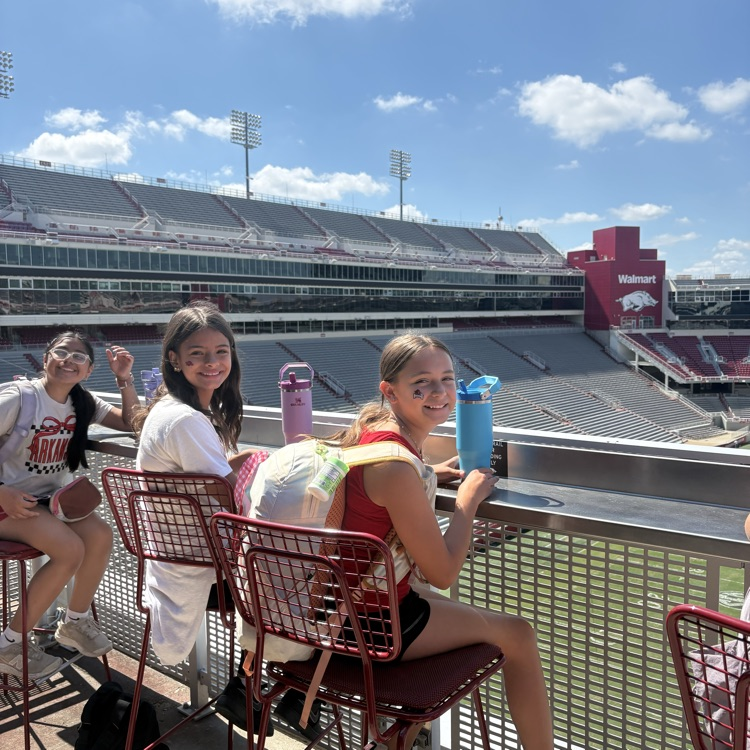 Students sitting at a perch overlooking the Razorback Football field