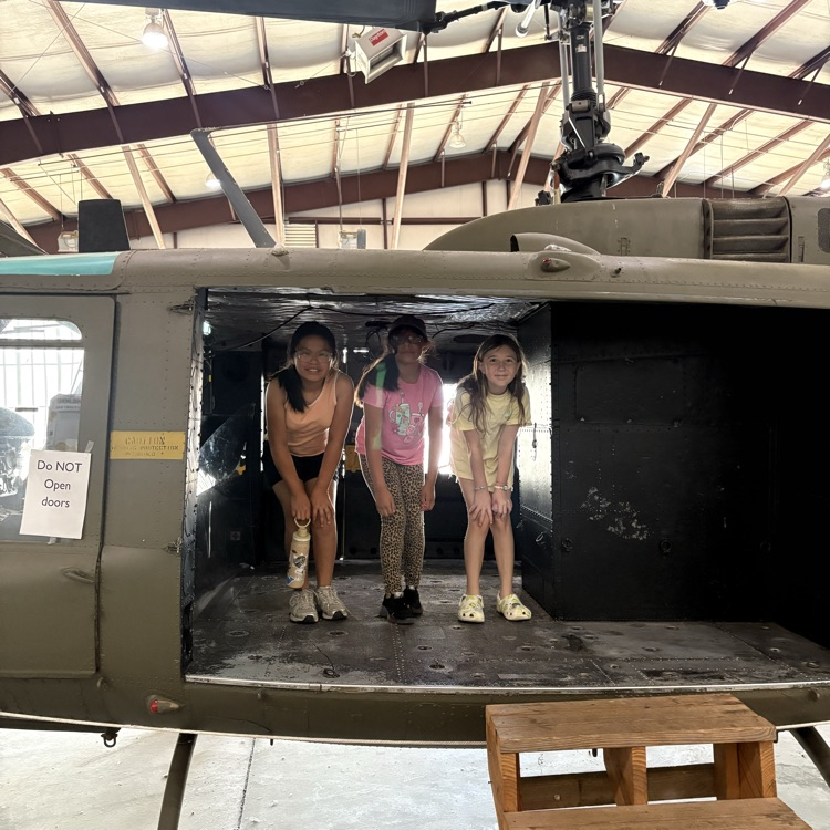 Students hunched over in a US Vietnam era helicopter at the Air and Military Museum