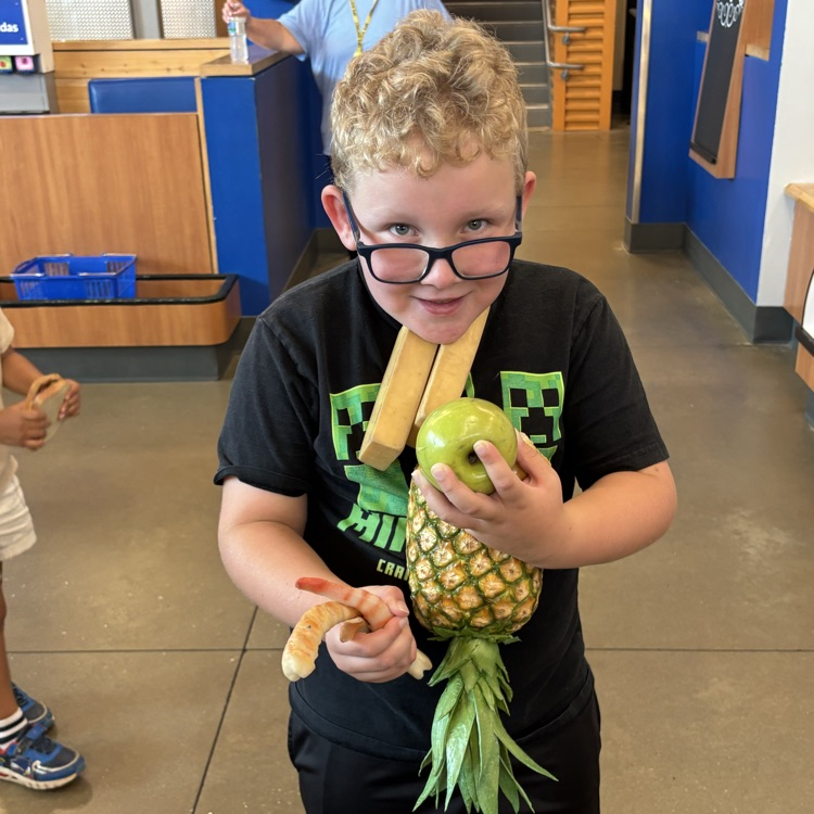 A student holding fake groceries in the Walmart play area at the Amazeum 