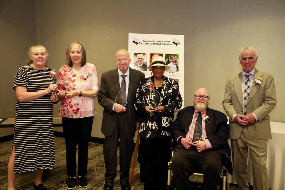 Recipients of the Alumni of Distinction award pose for a photo with their glass awards