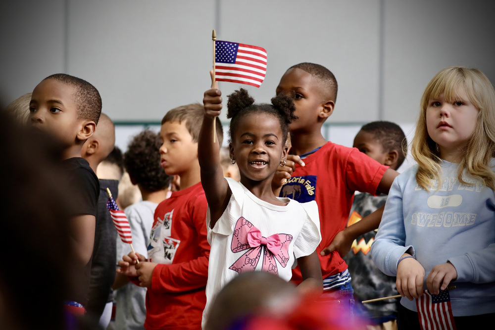 A student waves a flag at the Kenwood elementary Veterans Day ceremony