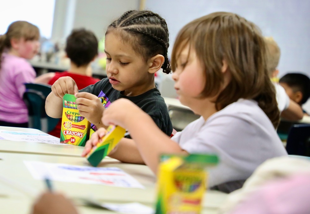 Students use crayons to color a picture