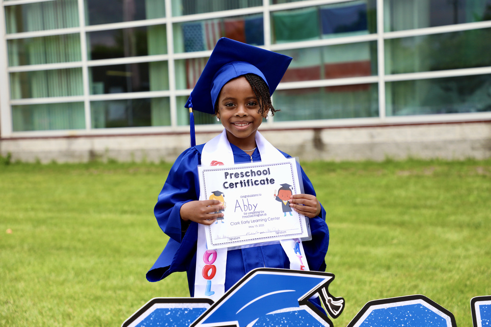 A clark preschool student holds their completion certificate after 'graduating'