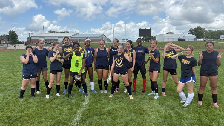 girls soccer players after the game holding up two fingers to signify a second place finish  