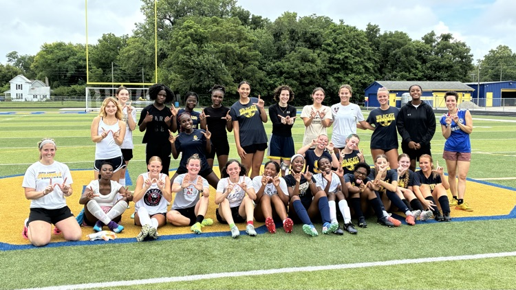 photo of soccer players posing for group picture after a soccer game 