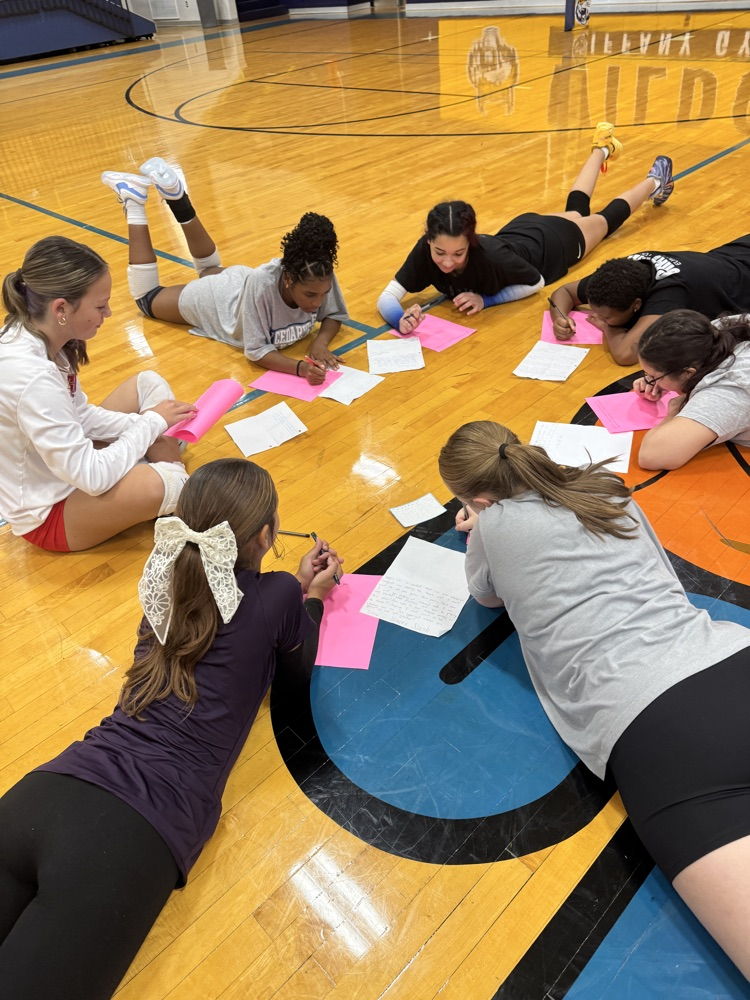 players work on writing pen pal letters in the gym 