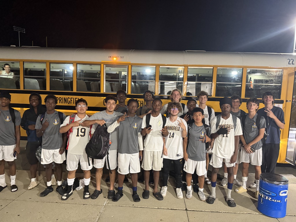 The boys soccer team poses for a picture in front of the bus