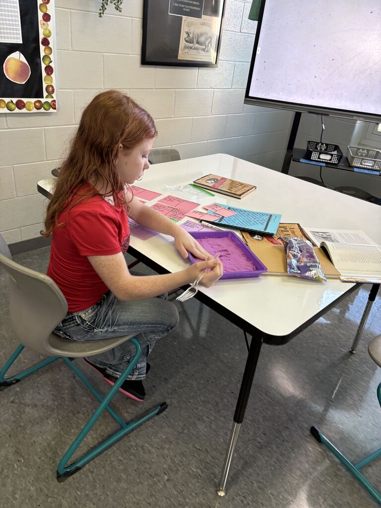 Students use kinetic sand and colored index cards to practice building complicated words with morphemes. 