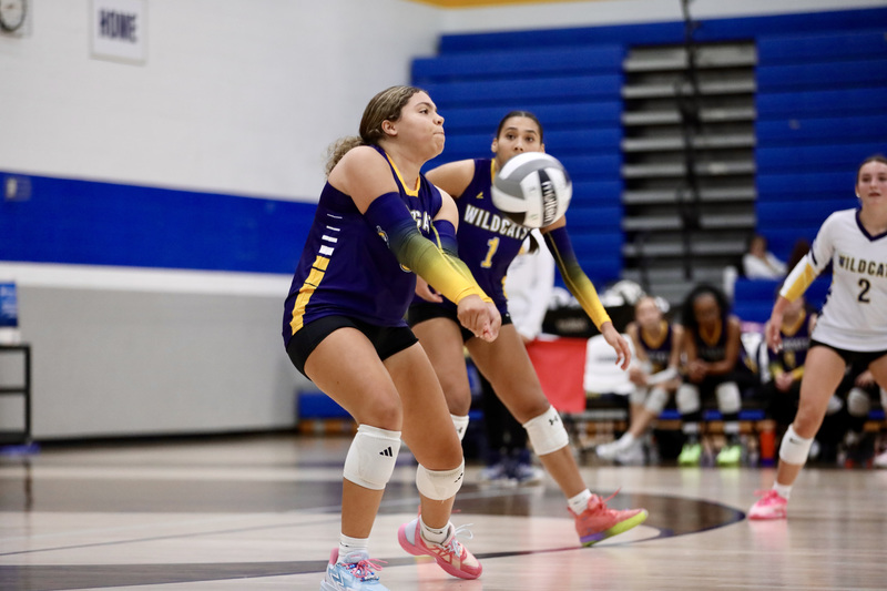 Maniya Soles digs a ball as her sister Paris backs her up