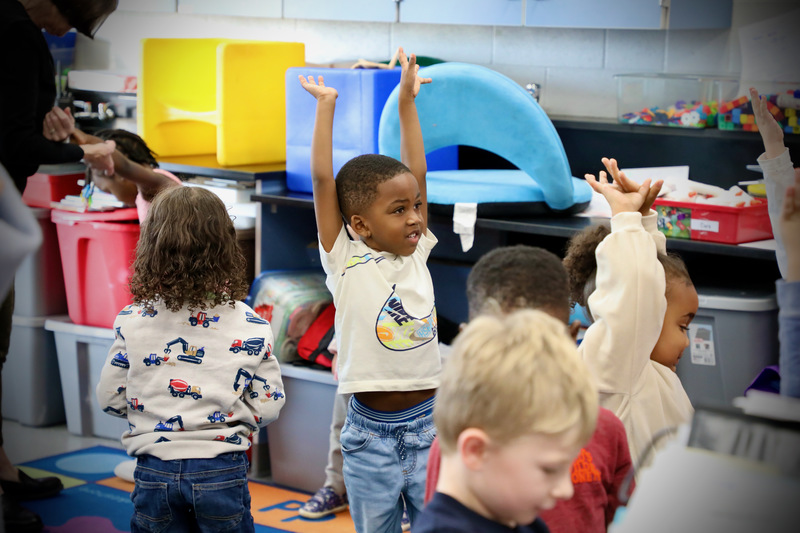 A preschool student stretches towards the sky