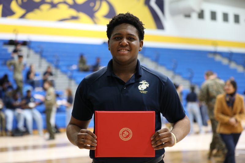 A student holds his award from the MJROTC ceremony