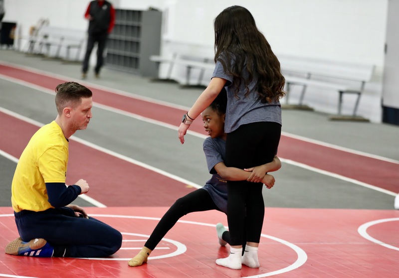 A student listens to instruction about how to do a wrestling takedown