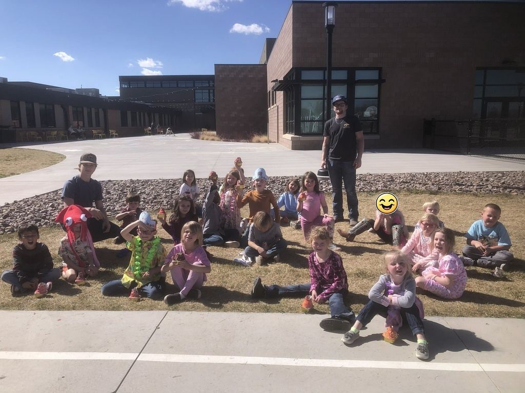 picture of students sitting on grass outside on playground