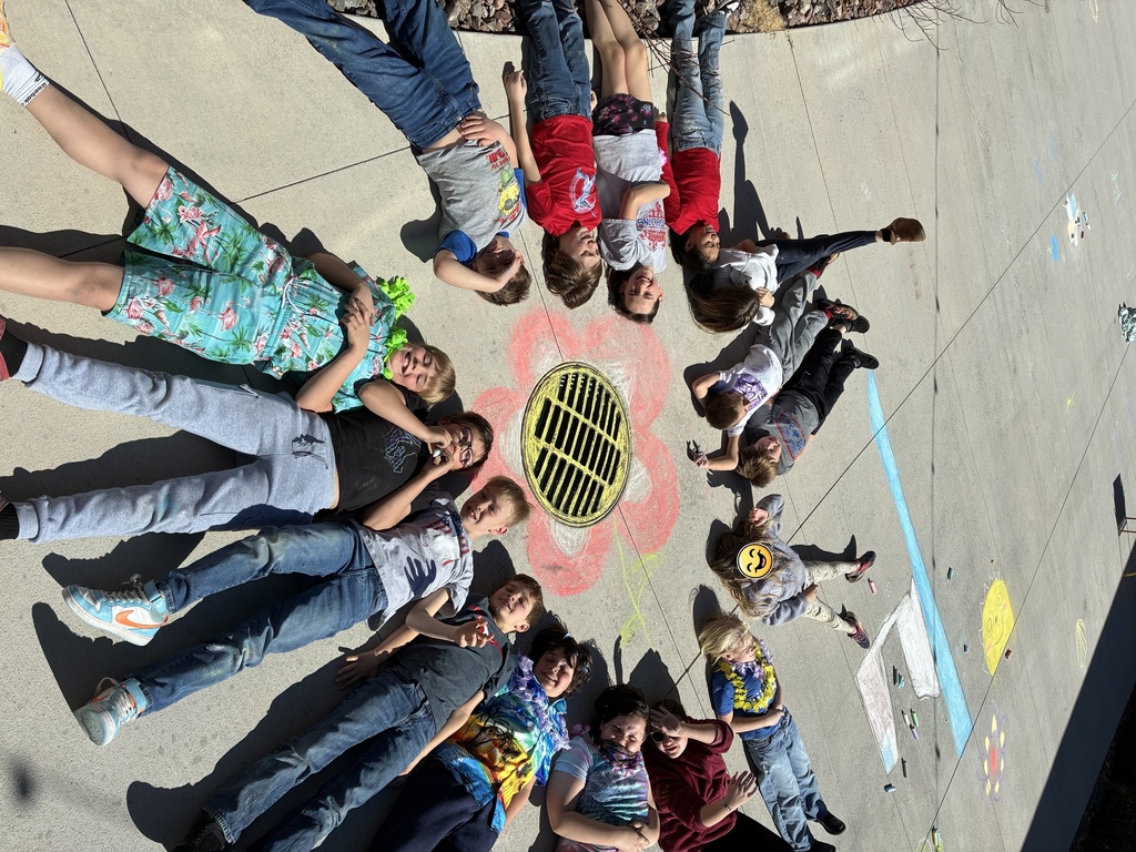 picture of students laying on ground around sidewalk chalk drawings