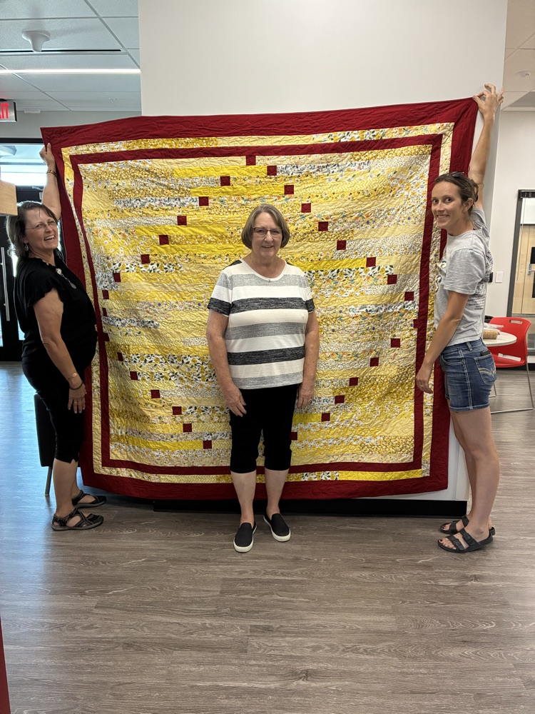 picture of Deb and Emily Sharpe presenting a quilt to Pam Hartley 