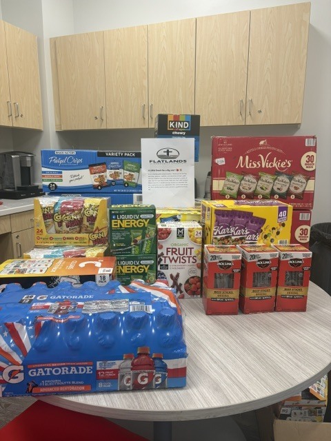 A table filled with donated snacks and drinks from Flatlands Community Church, including Gatorade, flavored water, fruit snacks, granola bars, popcorn, energy snacks, and other individually packaged treats for Springfield School District students.