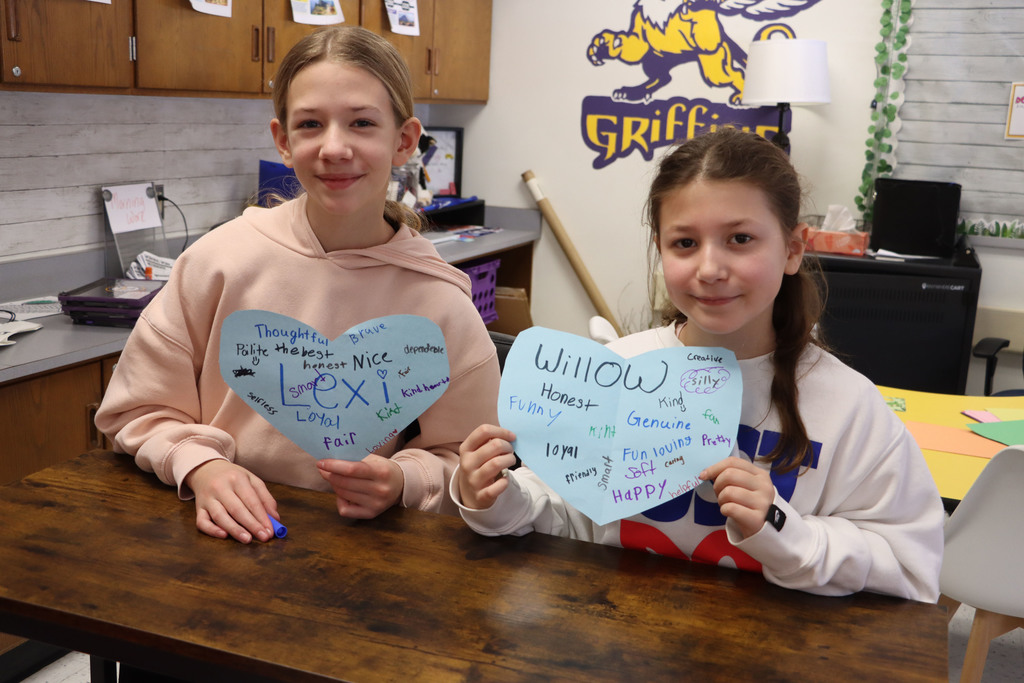 two students hold up character hearts.