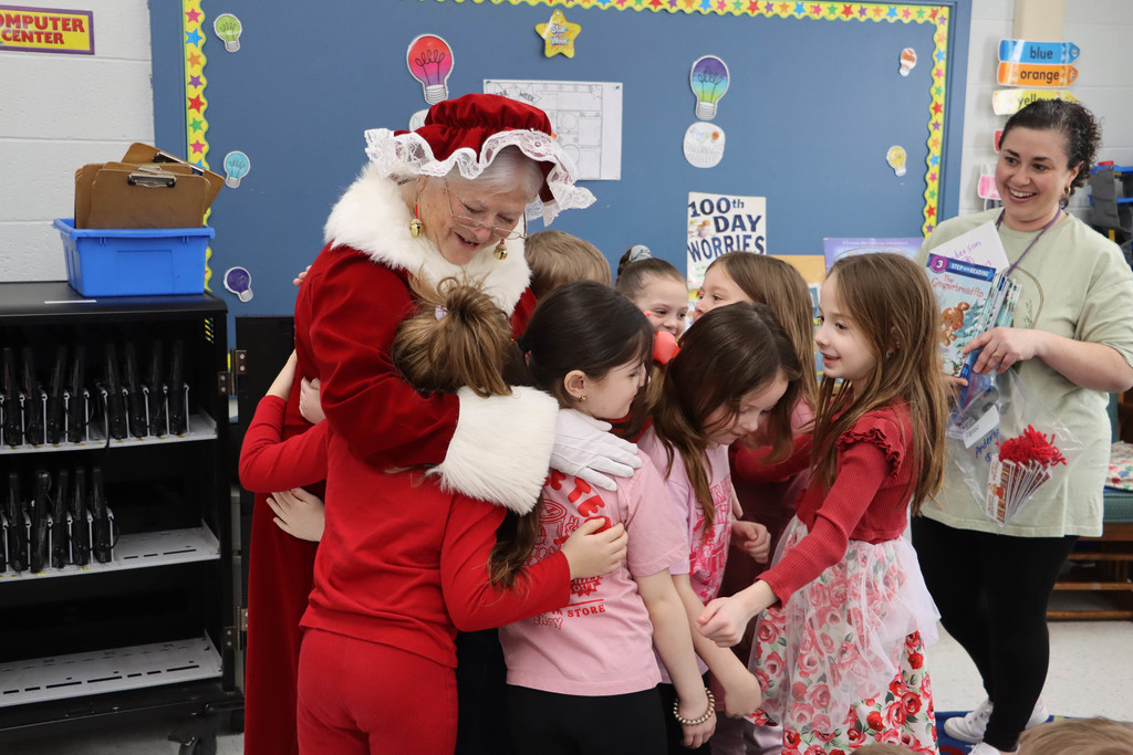 Mrs. Claus hugs students.