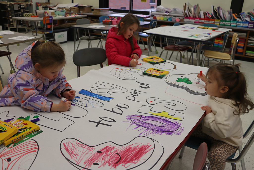 student color a poster that says "Lucky to be a part of CES".