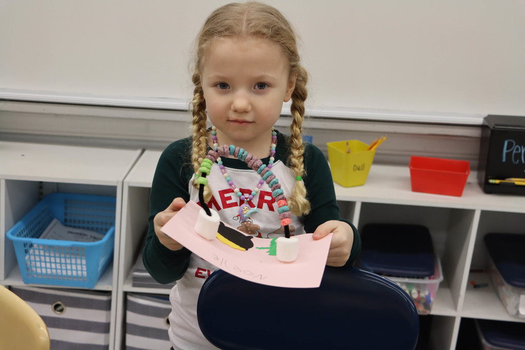 a student shows off her rainbow craft. 