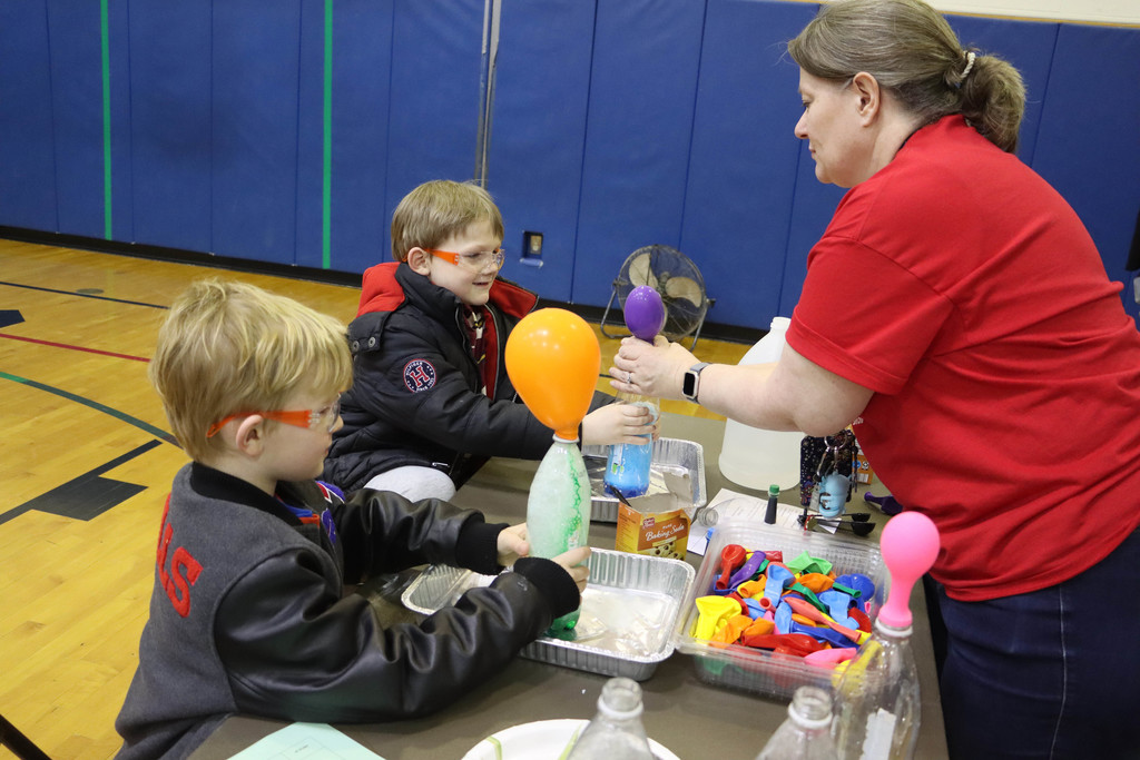 two students inflate a balloon with a reaction in a bottle. 