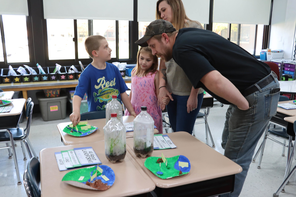 A student shows his classwork to his family. 