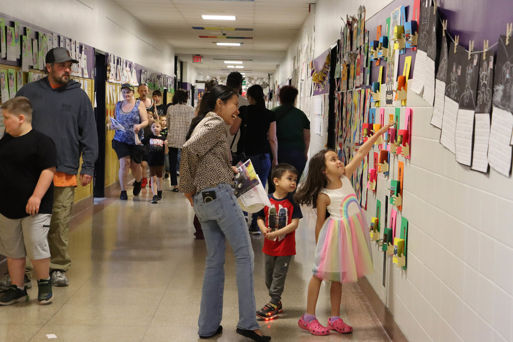 A student points out her artwork to her mom in the hall.