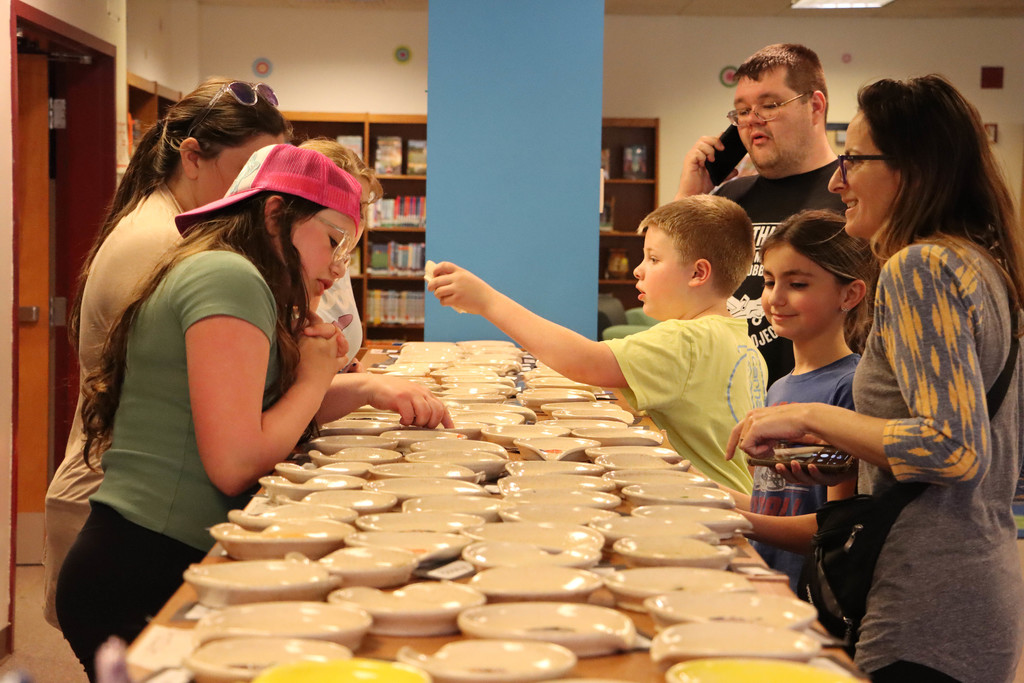 Students and their families admire their ceramics in the library. 
