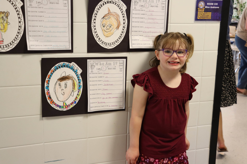 A kindergartner poses with her self portrait. 