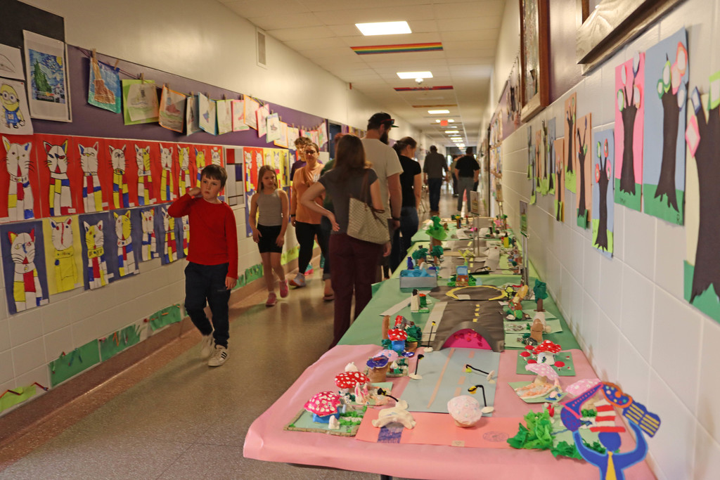 Families pass artwork in the halls of SES. 