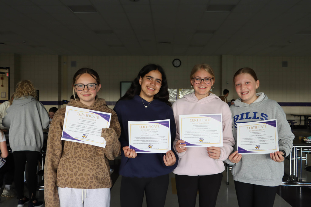 four students hold their certificates. 