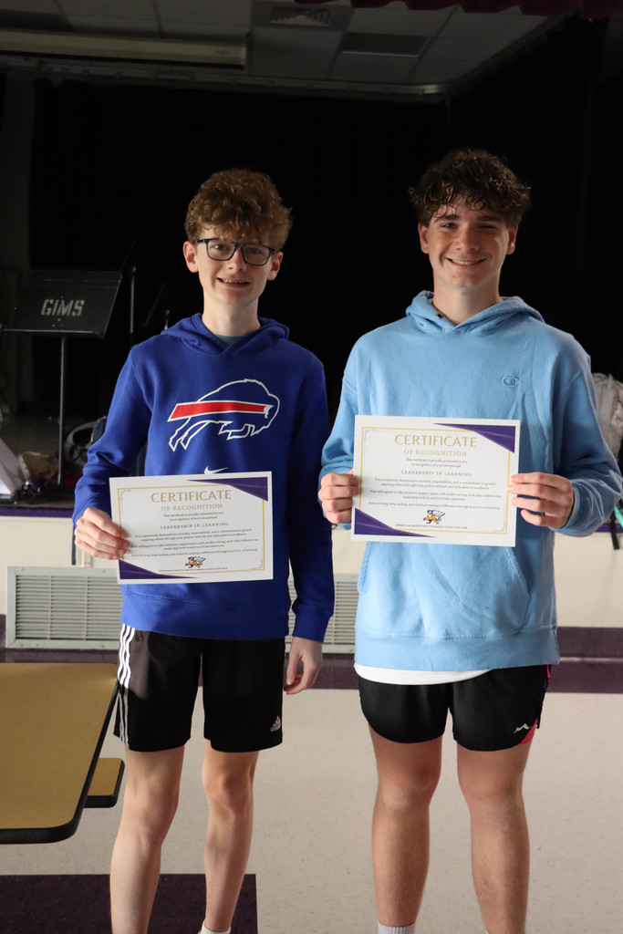 Two students hold their certificates. 