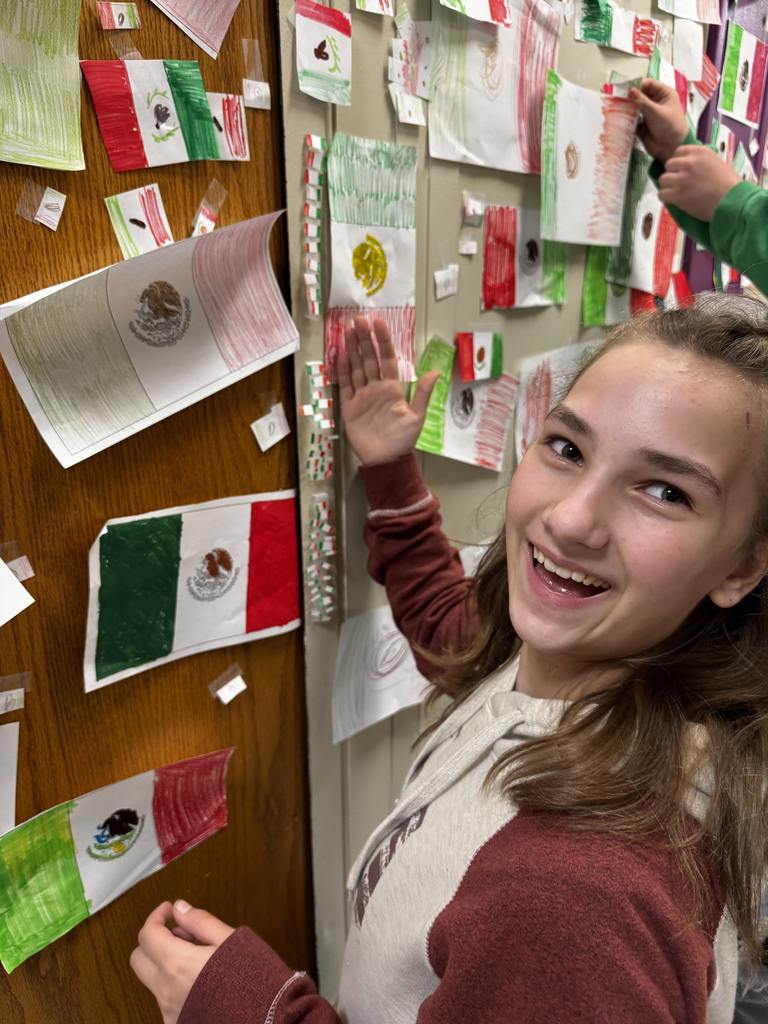 A student hangs up the Mexican flag during the flag war. 