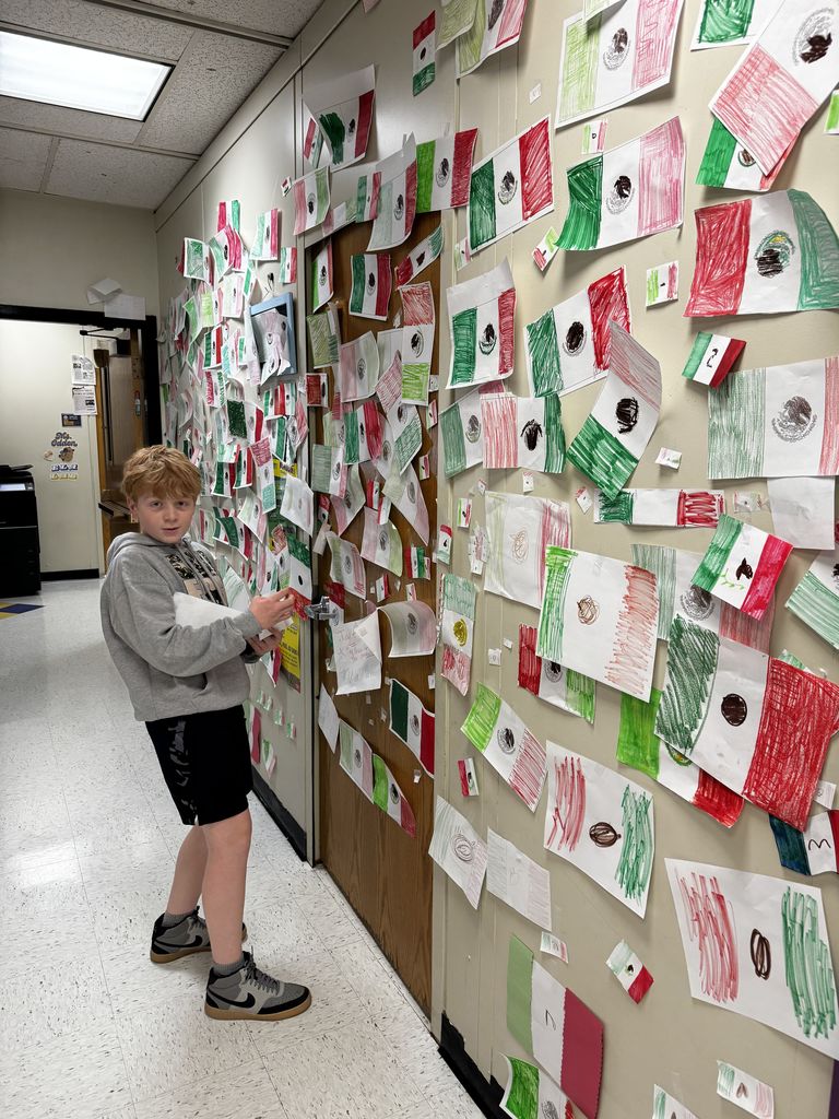 A student hangs up the Mexican flag during the flag war. 