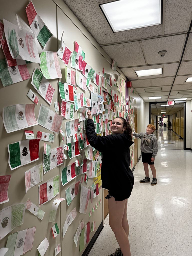 A student hangs up the Mexican flag during the flag war. 