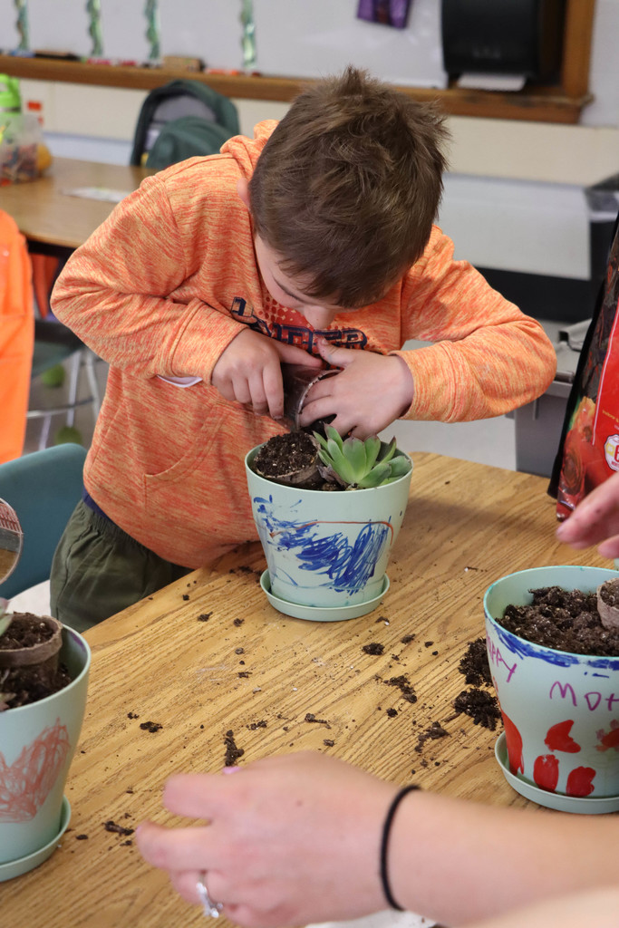 A student adds dirt to the pot