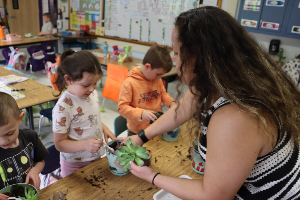 Mrs. Caldwell assists the students in planting. 