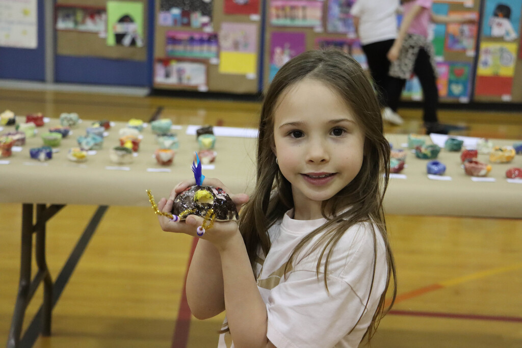 A student holds up her ceramic bird. 