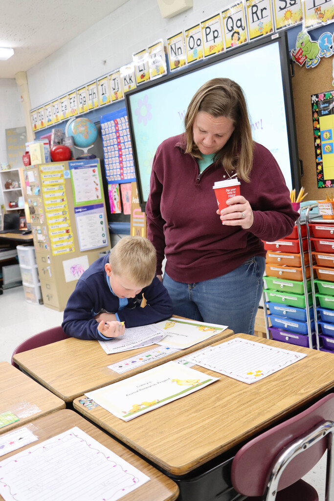 A student shows his parent his writing project. 
