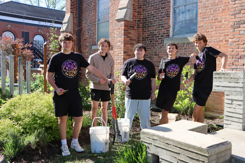 Five students pull weeds at The Center for the Arts. 