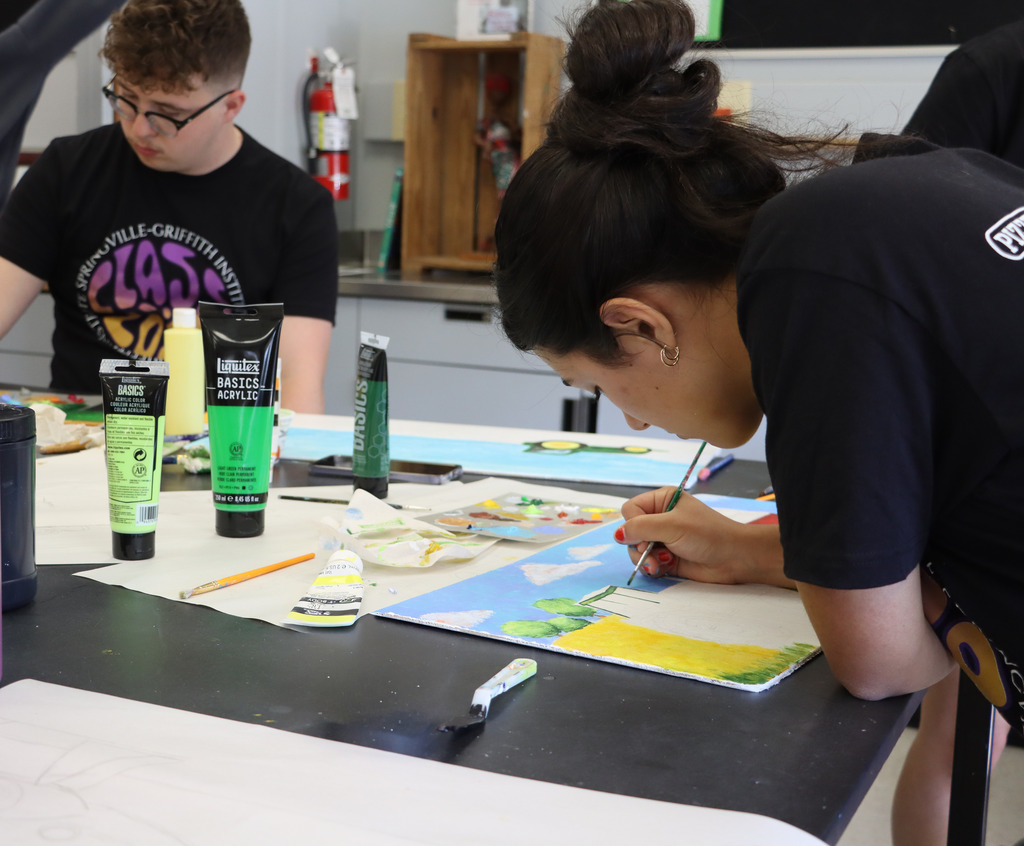 Two seniors paint tractors for the Art Crawl. 