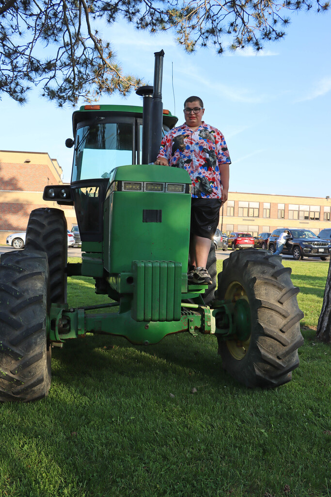 Student on large green tractor. 