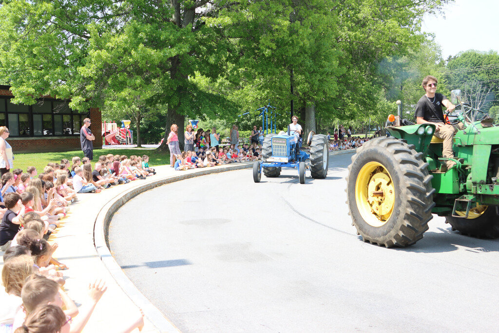 students on tractors drive by SES students