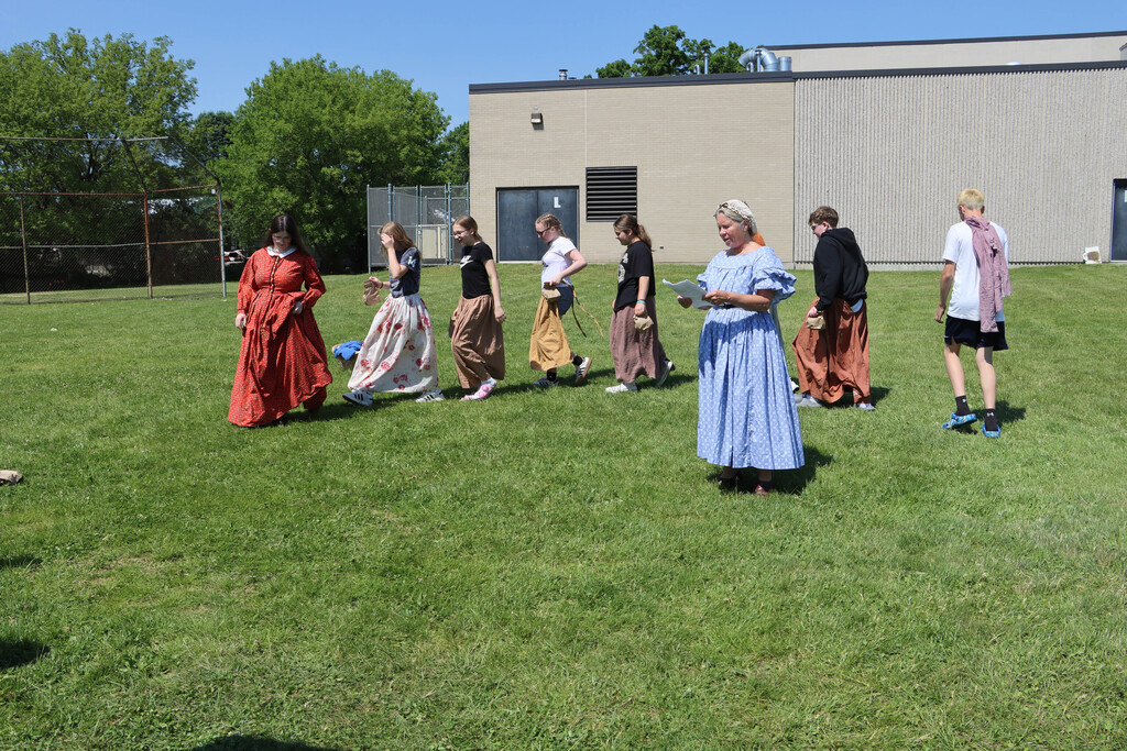 Students and re-enactors act out a play in costume. 