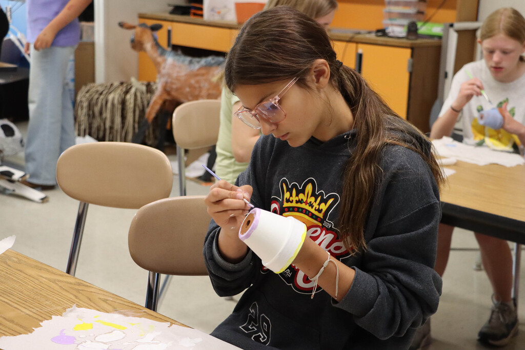 A student paints a plant pot. 