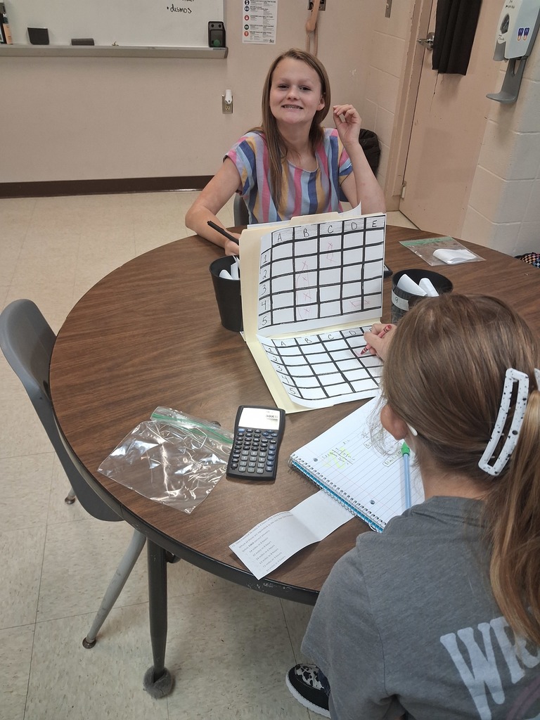 math squd battle ship game in action with paper and squares instead of the real battleship game, girl smiling