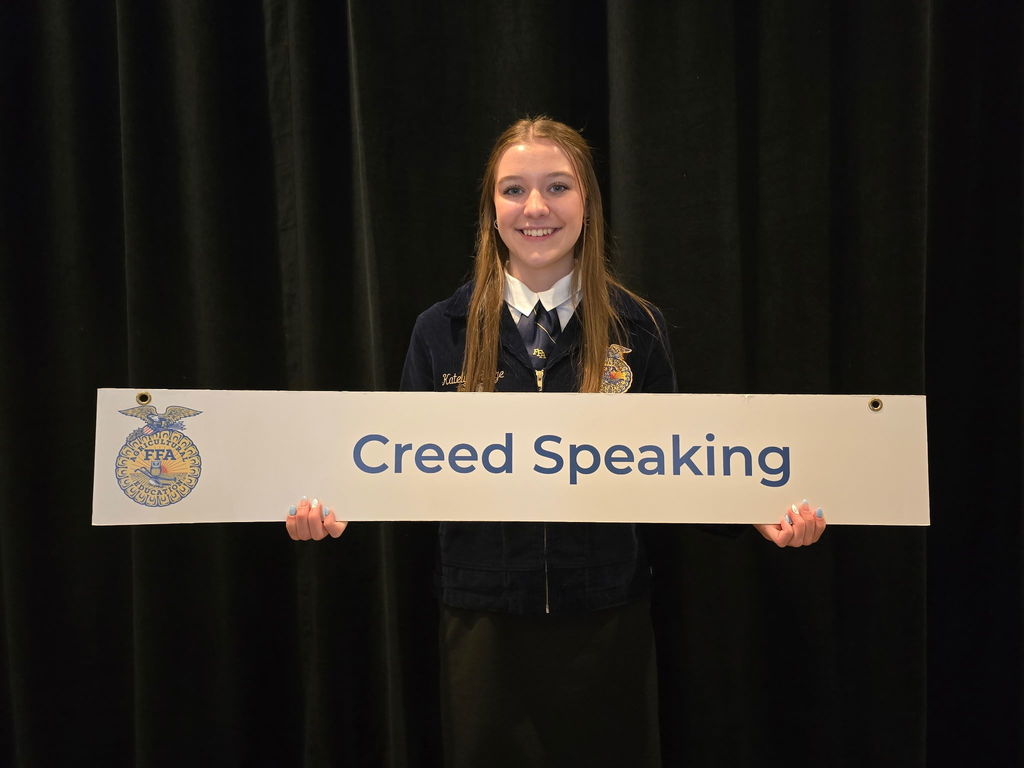Katelyn Runge holding a sign saying Creed Speaking
