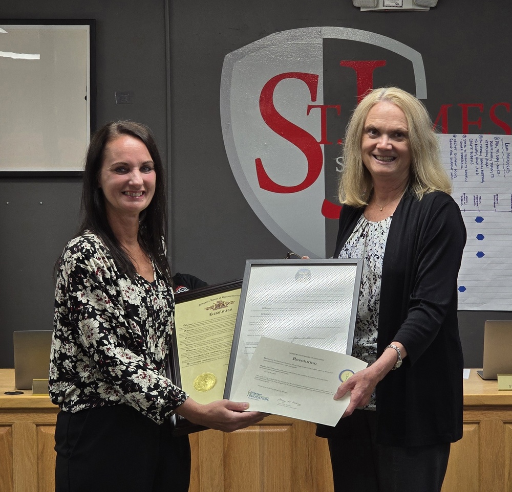 Two women stand together holding certificates. 