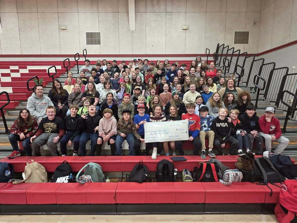 Entire 6th grade class sits in bleachers with a big check from IHOP for $500 for their field trip.